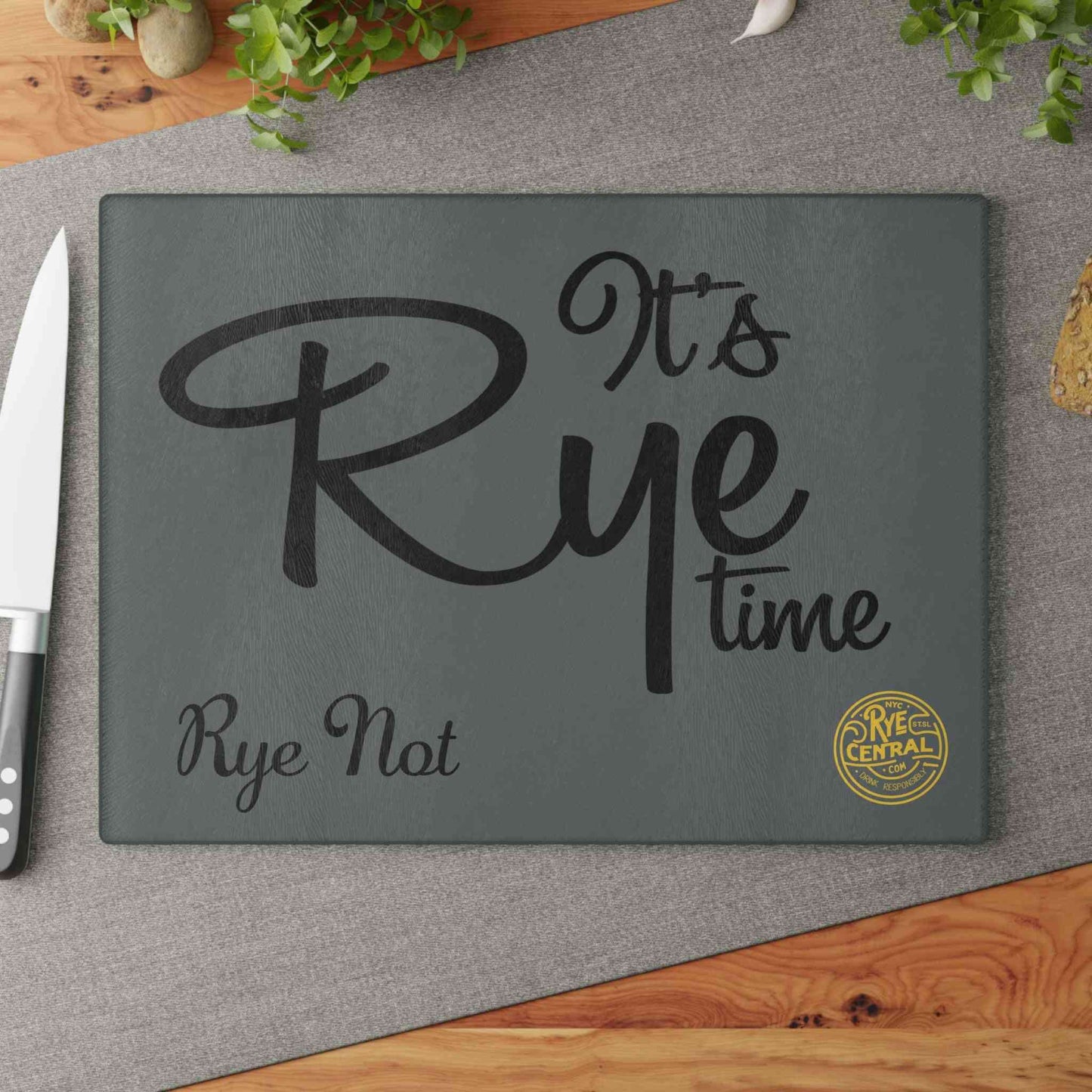 Tempered glass Whiskey Bar Cutting Board on kitchen table with knife and bread, combining function and whiskey-themed kitchen decor.