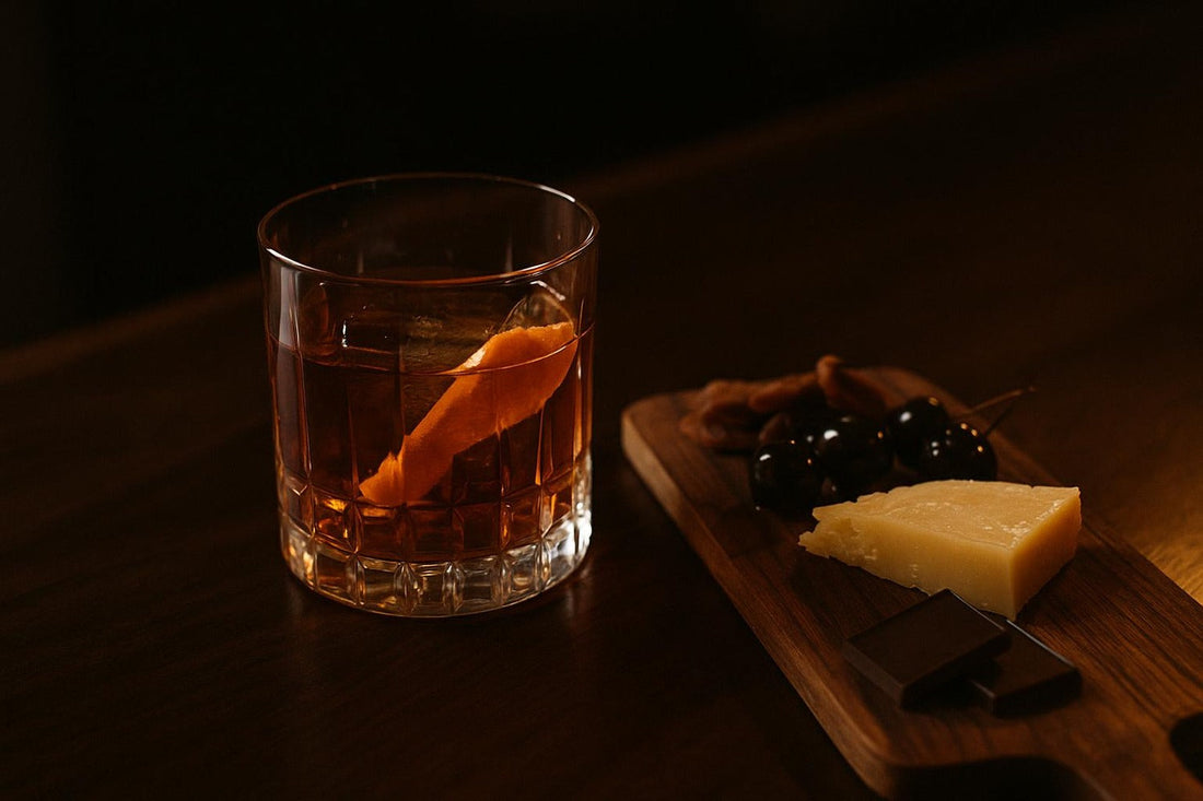 Old Fashioned beside charcuterie board with aged cheese, cherries, dark chocolate — Old Fashioned food pairing