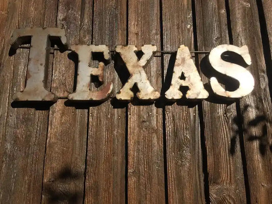 TEXAS RUSTIC RECYCLED METAL WALL DECOR featuring distressed metal letters mounted on a wooden wall, ideal for country-style accent décor.