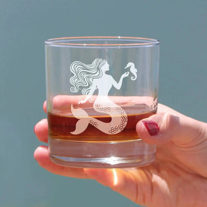 Outdoor shot of Mermaid Whiskey Glass in hand, filled with whiskey, ideal for beach-themed gatherings and seasonal drinkware collections.