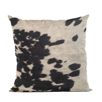 Woman holding luxury cowhide throw pillow with rustic black and white design, ideal for cozy whiskey-inspired interiors.