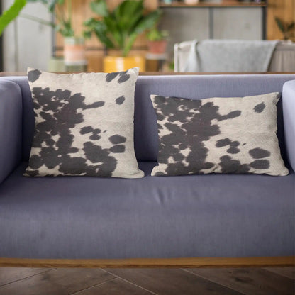 Close-up of luxury cowhide throw pillow texture, highlighting soft black and white fur pattern for rustic home accents.