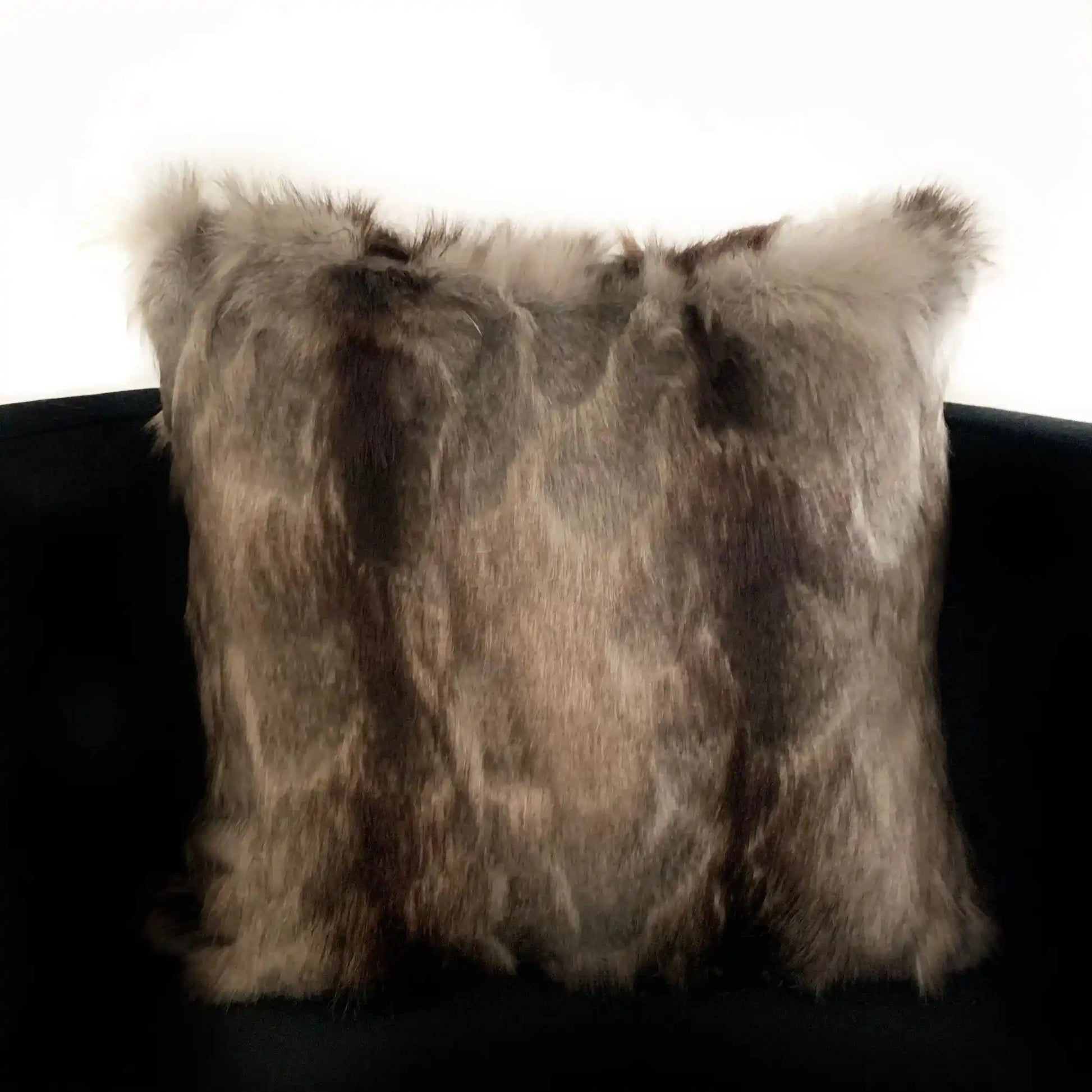 Angled view of luxury faux fur throw pillow on a chair, highlighting its soft, multi-toned fur for sophisticated home decor.