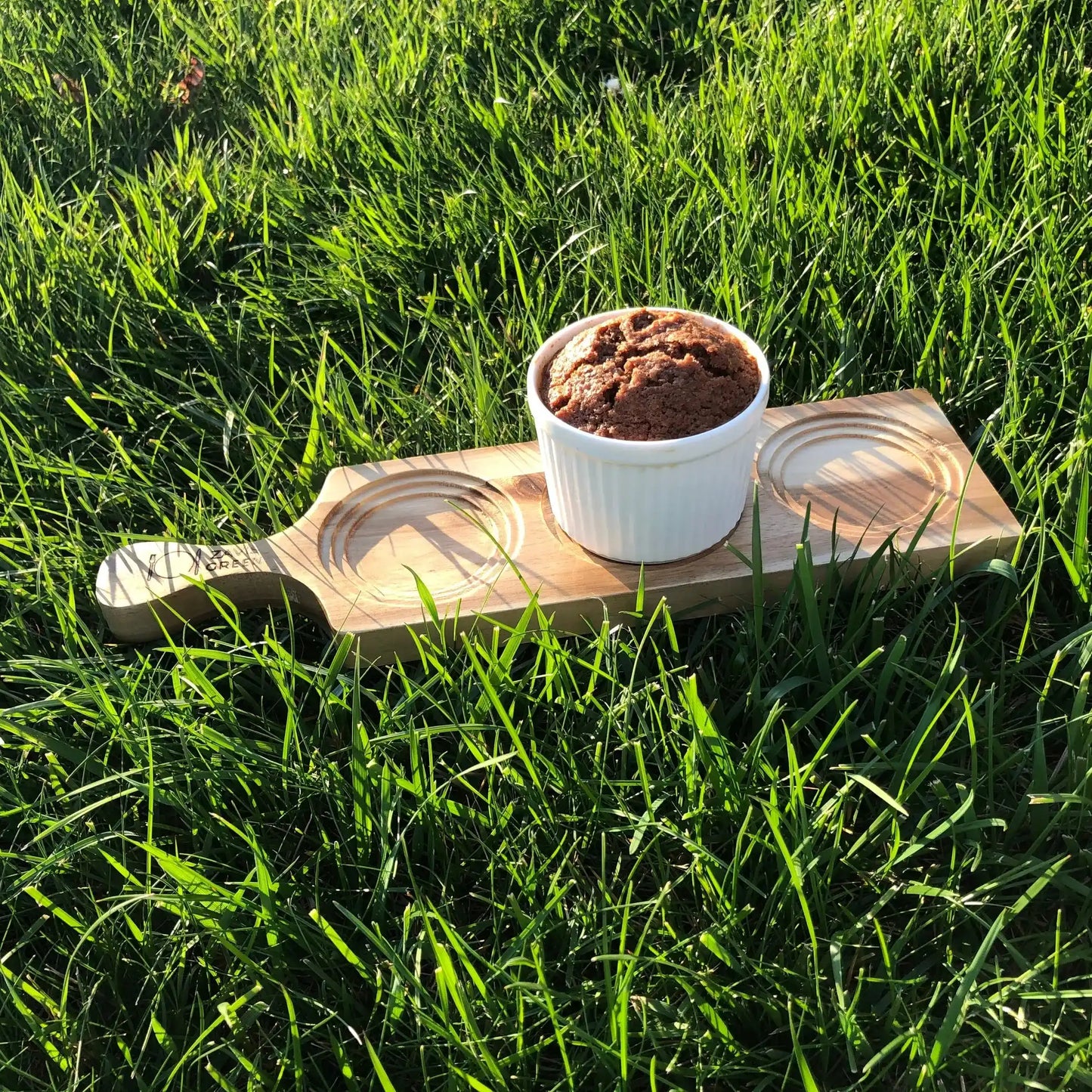 Underside of Acacia Flight Board with 3 square slots, perfect for whiskey glasses, displayed on green grass for rustic appeal.