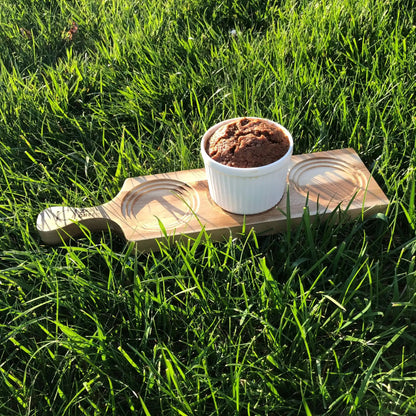 Underside of Acacia Flight Board with 3 square slots, perfect for whiskey glasses, displayed on green grass for rustic appeal.