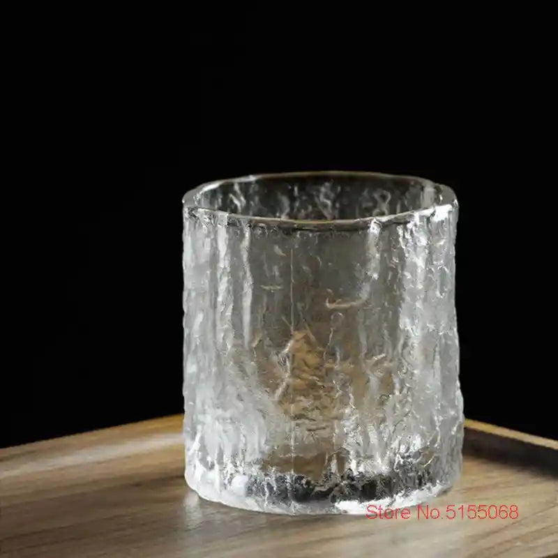 Empty frosted whiskey tumbler with textured crystal glass and Nordic Japanese design on wooden tray, ideal for stylish drinkware collections.