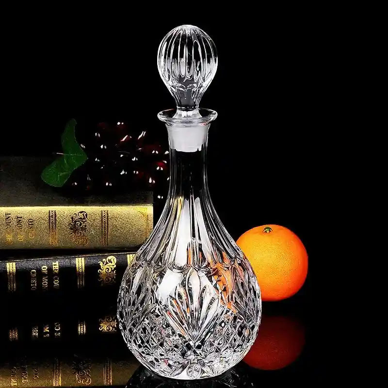 Vintage-style crystal glass wine decanter with round stopper, ideal for whiskey or wine, placed beside books and fruit for decor.