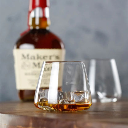 Whiskey glass with ice cubes and whiskey bottle in background