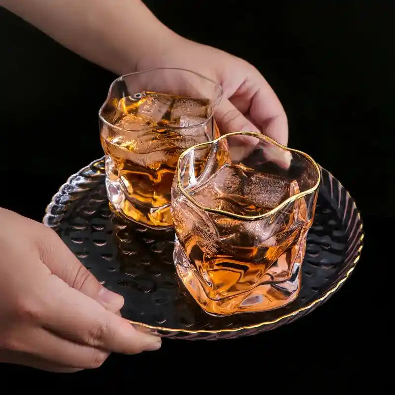 Two Japanese style twisted whiskey glasses with gold rim served on a tray, showcasing elegant design for scotch and cocktail drinks.