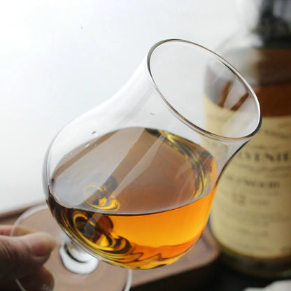 Close-up of whisky glass with amber spirit on wooden surface
