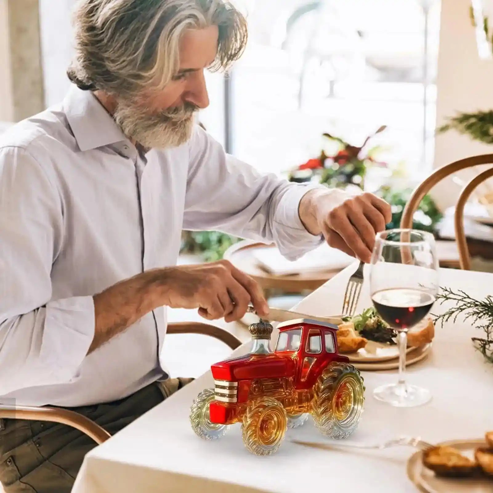 Red Glass Tractor Decanter on a dining table beside a wine glass, enhancing the meal with a touch of novelty and elegance.