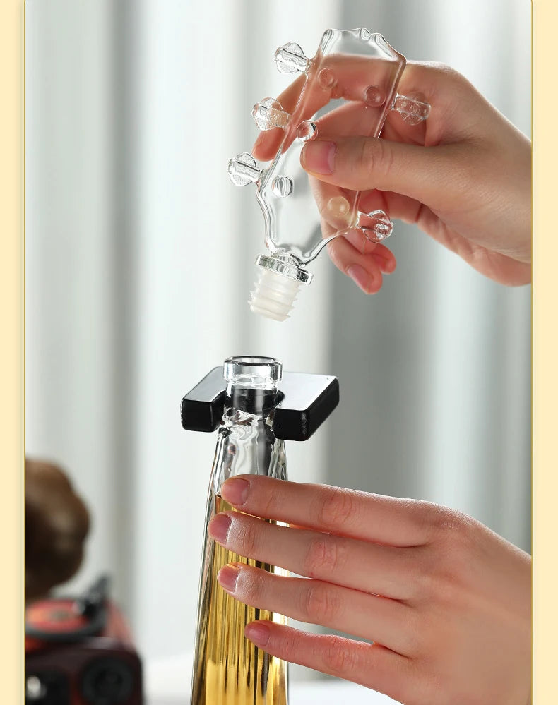 Hand holding glass violin decanter pouring into bottle