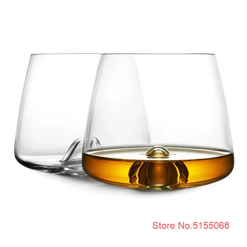 Clear whiskey glasses with whiskey on black surface