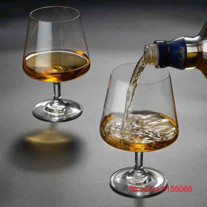 Whiskey glasses with pouring whiskey on dark surface