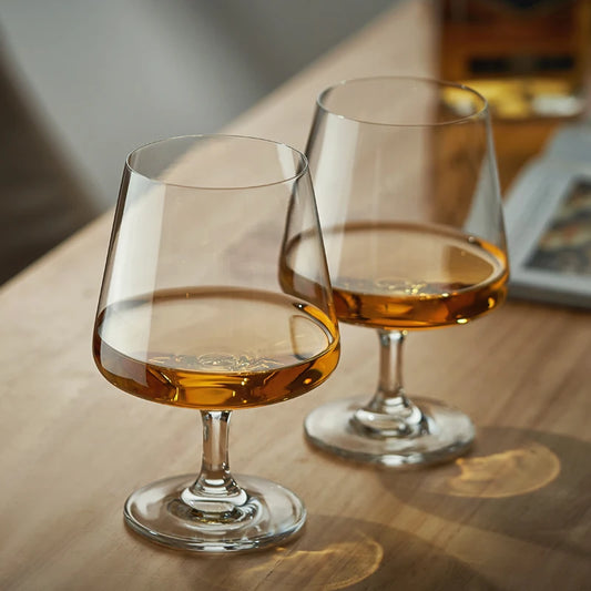 Elegant whiskey glasses with amber liquid on wooden table